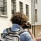 Back view of photographer with backpack on the street taking photo in historic italian city. Mantova, Italy