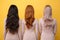 Back view picture of young three ladies over yellow background.