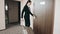 Back view portrait of a business woman in skirt suit on high heels walking with her suitcase along hotel lobby