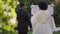 Back view portrait of happy loving affectionate couple holding hands looking at each other talking with wedding altar at