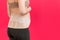 Back view of pregnant woman wearing pregnancy belt at pink background with copy space. Close up of orthopedic abdominal support