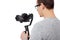 Back view of professional videographer using dslr camera on gimbal stabilizer isolated on white, focus on camera