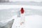 Back View red hair woman walking outdoors on the snow to the frozen frosty lake for the ice bath while snowing