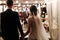 Back view of romantic couple of bride and groom on banquet hand in hand. The lights of the electric garland illuminate the wedding