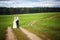 Back view of romantic couple of bride and groom walking hand in hand on rural road.