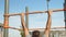 Back view of senior sporty man doing pull ups on horizontal workout outdoors