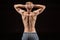 Back view of shirtless bearded bodybuilder posing isolated on black