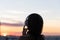 Back view silhouette of relaxed woman wearing headphones meditating listening to music on the beach at sunset.