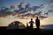 Back view silhouettes of female and kid stand near camping at daybreak