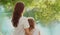 Back view silhouettes of mother and child together on lake in summer