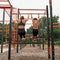 Back view of slim mother and son on horizontal bar