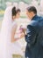 Back view of the smiling newlywed couple sitting on the old fountain.