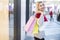 Back view of a smiling young woman standing and holding shop bags while looking back to camera in a shopping center