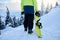 Back view of snowboarder climbing with his board on the mount for backcountry freeride session in the forest. Man with