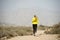 Back view sport runner girl training on earth trail dirty road desert mountain landscape