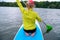 Back view of a sporty girl with white hair sitting on a board with a paddle on the river