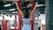 Back view of sporty woman doing pull ups in gym