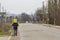 Back view of strong athletic man father carrying on shoulders young child in warm bright clothing walking along suburb road on coo