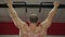 Back view of strong male athlete with muscular arms and shoulders hanging on bar