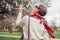 Back view of stylish woman walking with red hair scarf in spring park. Retro female fashion. Headscarf for bun hairstyle