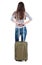 Back view of stylishly dressed brunette woman with suitcase lo