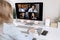 Back view of successful business waving hello to colleagues on video meeting. Stylish female employee is sitting at the