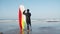 Back view of surfer with disability standing next to ocean