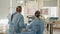 Back view of surgeons team looks at monitors while preforming operation in hospital operating theater, male surgeon