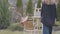 Back view of the tall young girl painter comes and sits in front of wooden easel to draw a picture. Lady is smoking