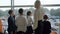 Back view of teacher and schoolchildren looking out the window and talking. Group of cute Caucasian boys and girls