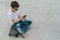 Back view.Teenager sits on skateboard,uses smartphone,digital gadget, plays computer games, browsing internet, chatting.