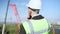 Back view thoughtful Caucasian foreman standing at industrial park with tower crane looking away. Young confident man