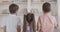 Back view of three children pointing at bookshelves and talking. Little Caucasian boys and girl discussing books indoors