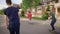 Back view of three friends riding skateboards in summer day. Young people in casual outfit skating along the street