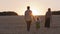 Back view three silhouettes from behind family walking outdoors in park sunset. Parents mother father with little