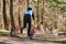 Back view to man musher rides on three wheeled cart with Siberian Husky sled dogs in harness