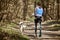 Back view to running Siberian Husky sled dog in harness pulling man on autumn forest country road