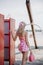 Back view to young blonde girl look like a Barbie doll in pink mini dress, pink bow with pink handbag coming out of changing room