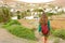 Back view traveler backpacker woman walking on Fuerteventura pathway to Betancuria small colonial town, Spain