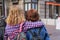 Back view of trendy teen girl friends hugging. Back view of two affectionate young students girls walking at street.