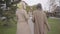 Back view of two beautiful Caucasian mature women in beige coats, headscarves and sunglasses walking in the city park