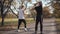 Back view of two Caucasian sportsmen warming up in the autumn park. Strong adult boys stretching before exercising