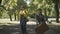 Back view of two cheerful hippie women walking along the road on sunny day, turning to camera, and waving away. Relaxed