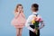 Back view, two little children boy with flowers and surprised girl in pink dress