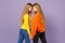 Back view of two pretty blonde twins sisters girls in vivid clothes holding hands, looking at each other  on