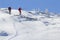 Back view of two tourist hikers with backpacks and hiking poles ascending snowy mountain slope on sunny winter day on white snow