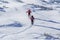 Back view of two tourist hikers with backpacks and hiking poles ascending snowy mountain slope on sunny winter day on white snow