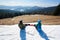 Back view of two tourists snowboarders on background of blue sky and mountains on sunny winter day.