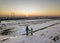Back view of two young children in warm clothing standing in frozen snow field holding hands on copy space background of setting
