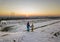 Back view of two young children in warm clothing standing in frozen snow field holding hands on copy space background of setting